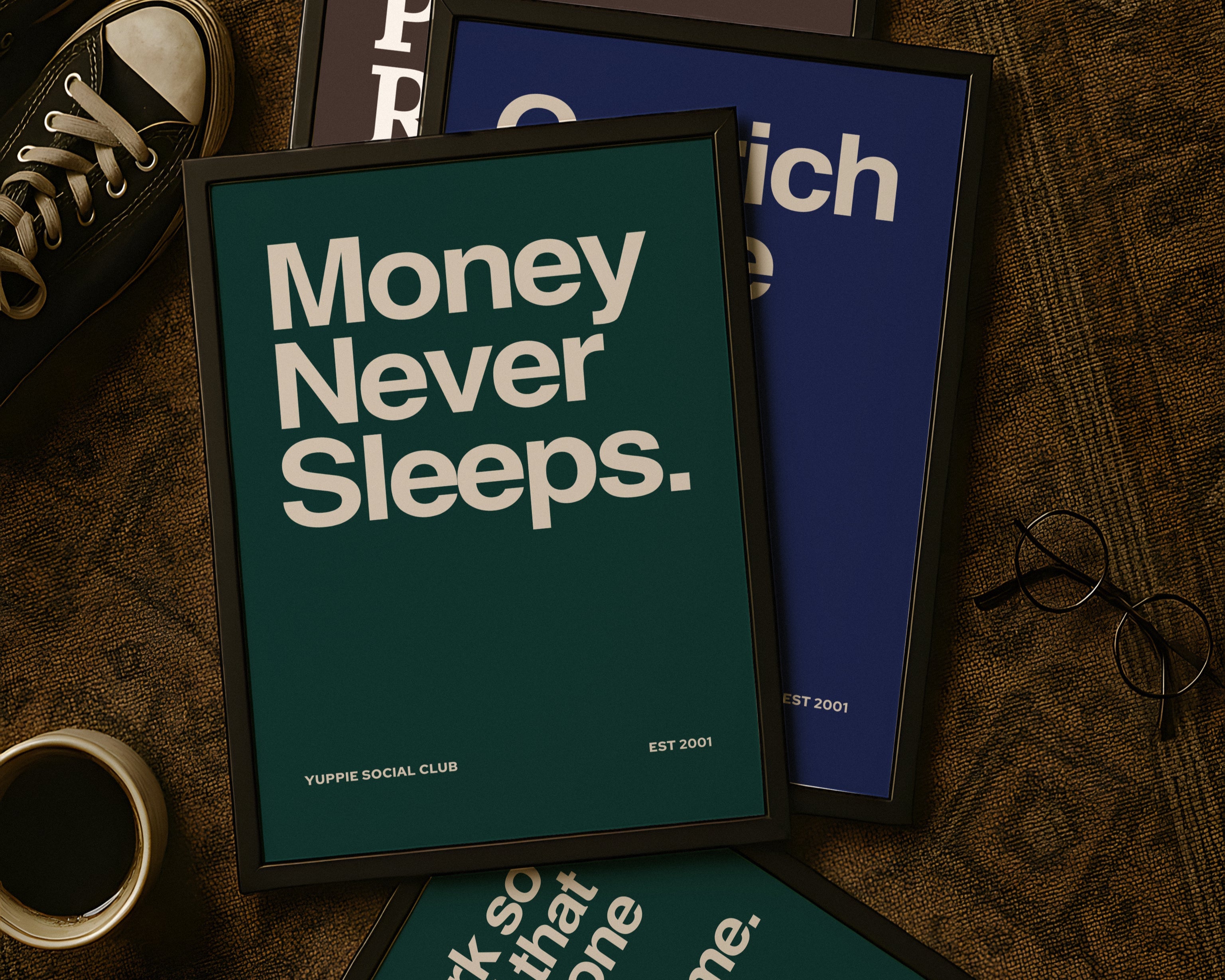Framed motivational posters on a textured surface with shoes and a camera.